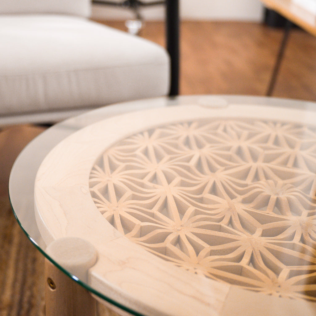 Table is made with maple and basswood with a glass top, displayed in a minimalist office.