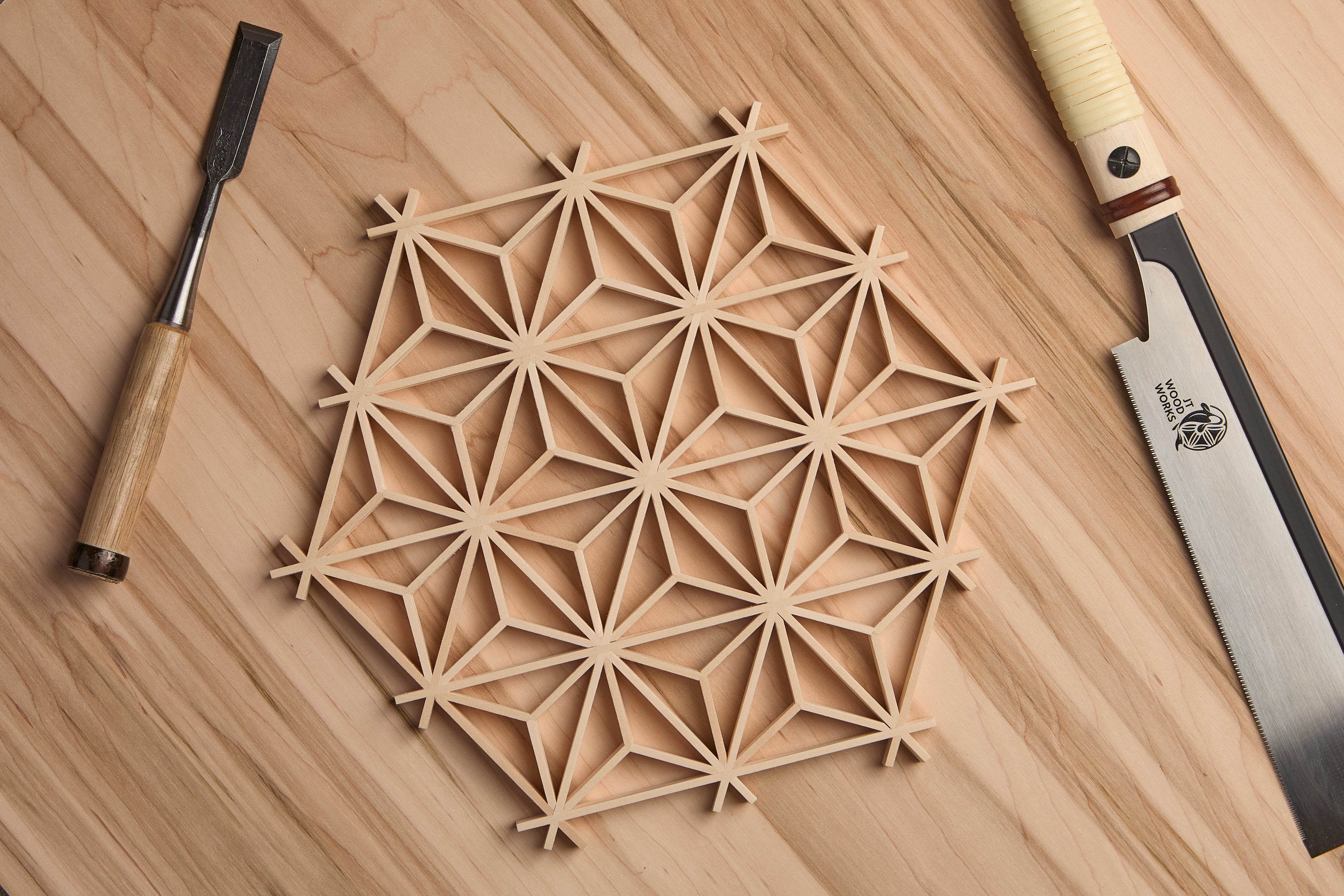 Wooden Asanoha kumiko pattern on a wooden surface with two chisels.