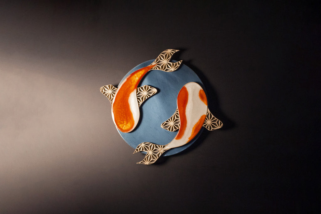 The Kumi-Koi is a handmade decorative art piece, as shown on a black wall.